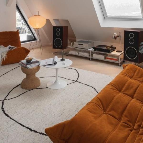 Salon lumineux sous le toit avec un tapis beige minimaliste à lignes noires.